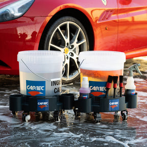 Kit professionale di lavaggio auto Cartec con secchi e accessori davanti a una Ferrari rossa.