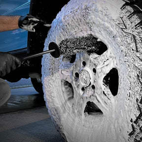  Detailer utilizza CARPRO Flat & Spot Brush per pulire accuratamente il cerchione di un'auto coperto di schiuma.