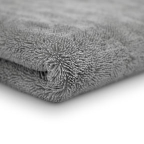 Dettaglio ravvicinato di un panno in microfibra grigio ultra assorbente, con una trama densa e soffice, ideale per asciugare l'auto senza lasciare tracce.
