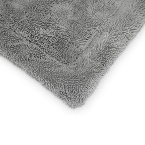 Dettaglio angolare di un panno in microfibra grigio ultra assorbente, perfetto per un'asciugatura delicata e senza aloni delle superfici auto.
