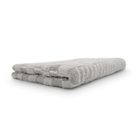 Panno asciugatura Stripped 2.0 in microfibra grigia, piegato, con un design a righe.
